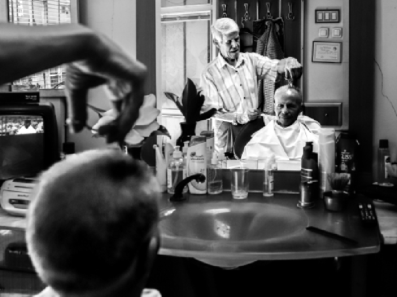 Κομμωτής κουρεύει ηλικιωμένο άνδρα